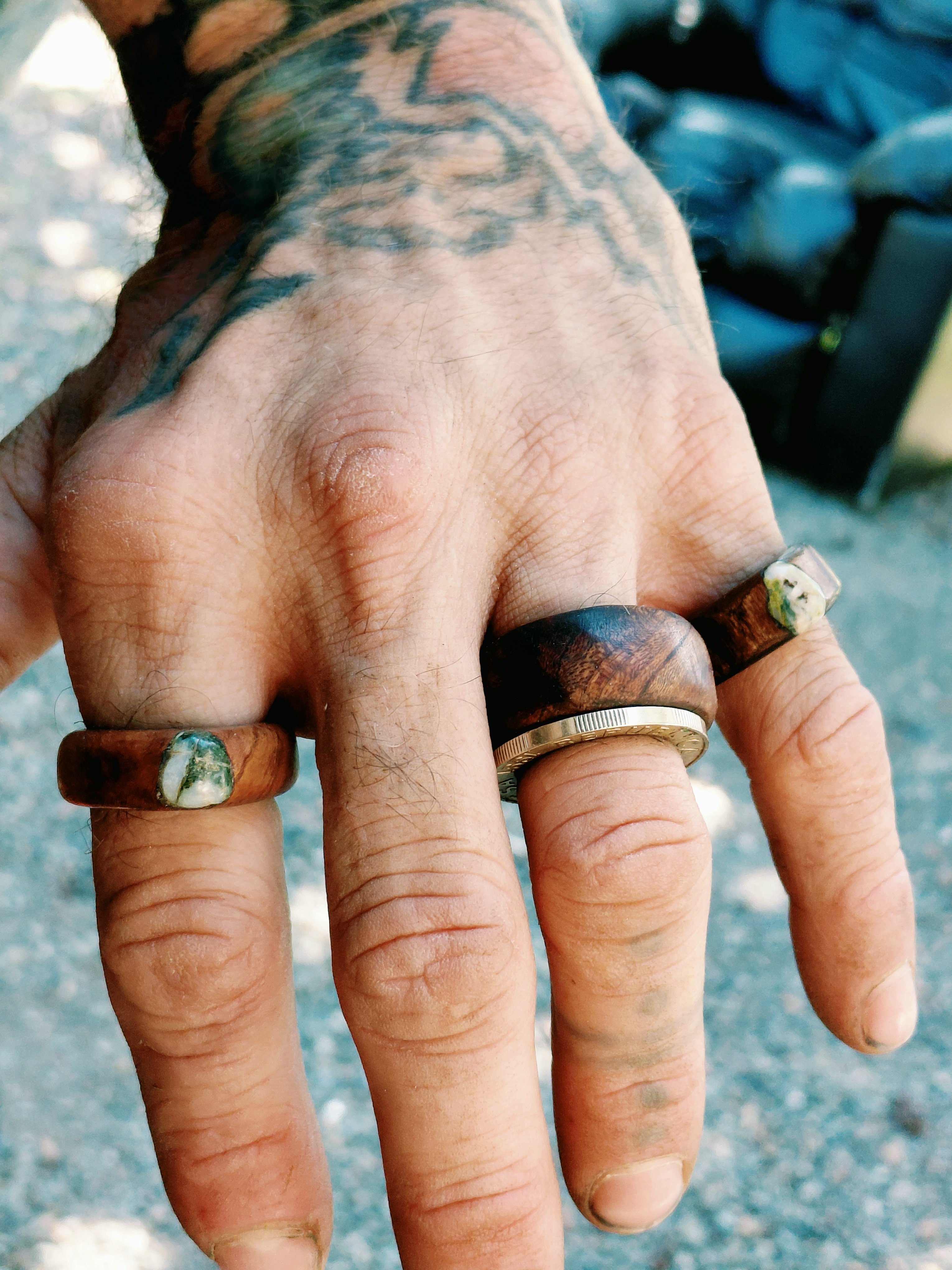 Three handmade wooden rings with stone inlays worn on one hand